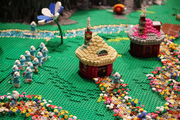 Ein LEGO-Modell einer Kleinstadt mit Häusern, Blumen, Spielzeugen, Pflanzen und anderen Gegenständen auf einem sanft unscharfen Hintergrund, der einen träumerischen Effekt erzeugt.