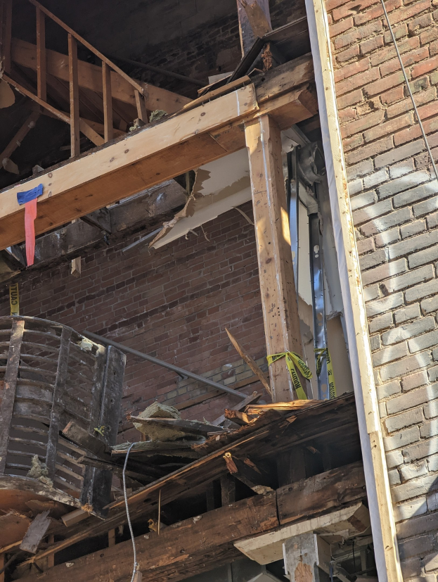 Teilweise abgerissener Bau mit verstreuten Holzplanken und Trümmern, zerbrochene Fenster und Türen im Anschluss an die Abrissarbeiten.
