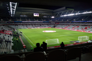 Großes Stadion voller Zuschauer bei einem Fußballspiel im Estadio Santiago Bernabeu in Madrid, Spanien, unter Stadionbeleuchtung mit einem Bildschirm oben.