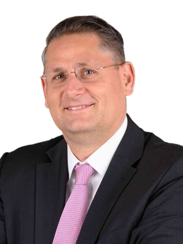 Ein lachender Mann im Anzug, mit Krawatte und Brille vor einem weißen Hintergrund, der auf einen Finanzberater hindeutet.