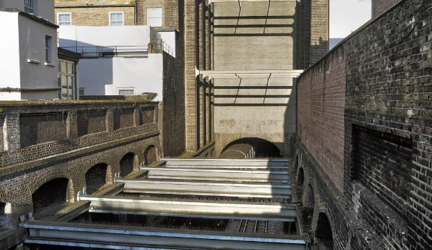 Ein Zug fährt durch einen Tunnel mit Gebäuden in der Nähe.