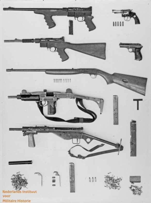 Schwarz-weiß-Foto von verschiedenen Waffen, Munition und Gegenständen, die auf einer Oberfläche verstreut sind, mit Text unten.