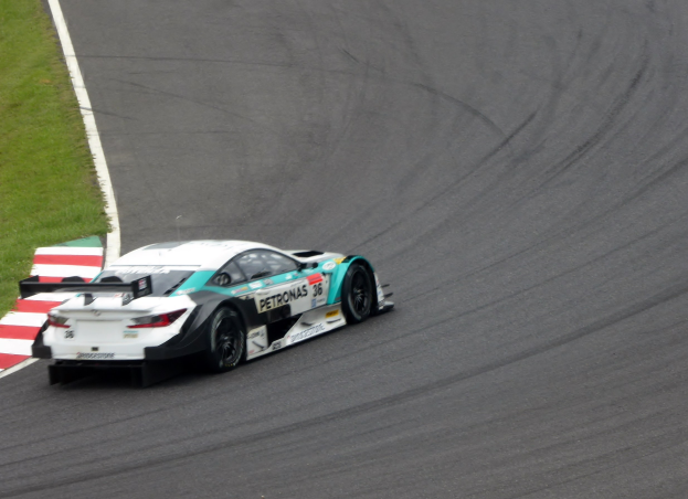 Mercedes-AMG GT3-Rennwagen auf einer Rennstrecke mit Text auf der Karosserie und Gras links.