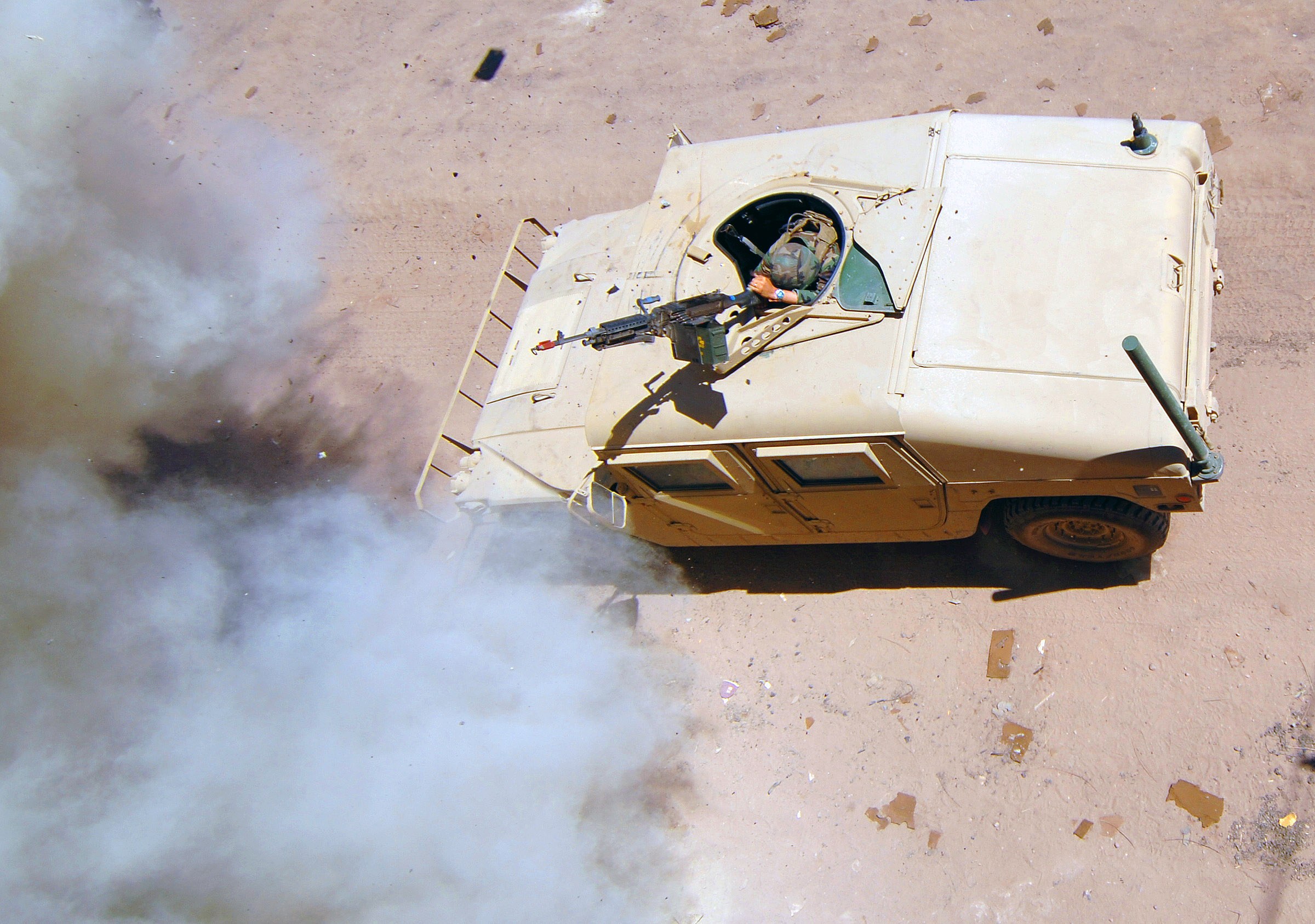 Panzerfahrzeug fährt auf einem Schotterweg mit Rauchentwicklung und einer Person im Inneren.