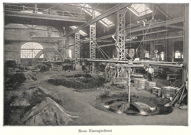 Schwarz-weiß-Fotografie eines Fabrikinneren mit Arbeitern, die Maschinen bedienen, Metallstangen und -stangen, beschriftet mit "Neue Eisenglebeerei, die erste Fabrik in Deutschland" unten.