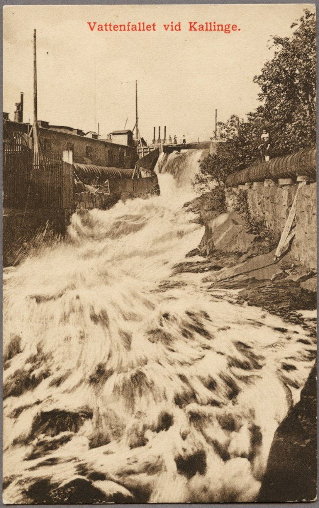 Altes Schwarz-Weiß-Foto eines Flusses mit fließendem Wasser, Bäumen, Gebäuden, Strommasten und einem Zaun; Text erscheint oben.