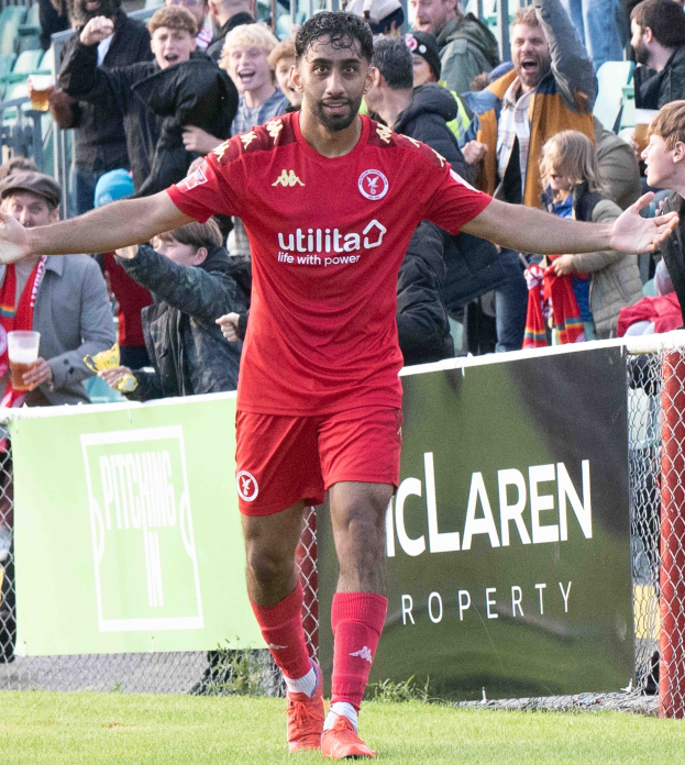Ein Fußballspieler in roter Uniform rennt auf einem Feld mit ausgestreckten Armen, umgeben von Zuschauern, mit einem "Middlesbrough FC v Swansea City - Sky Bet Championship"-Banner im Hintergrund.