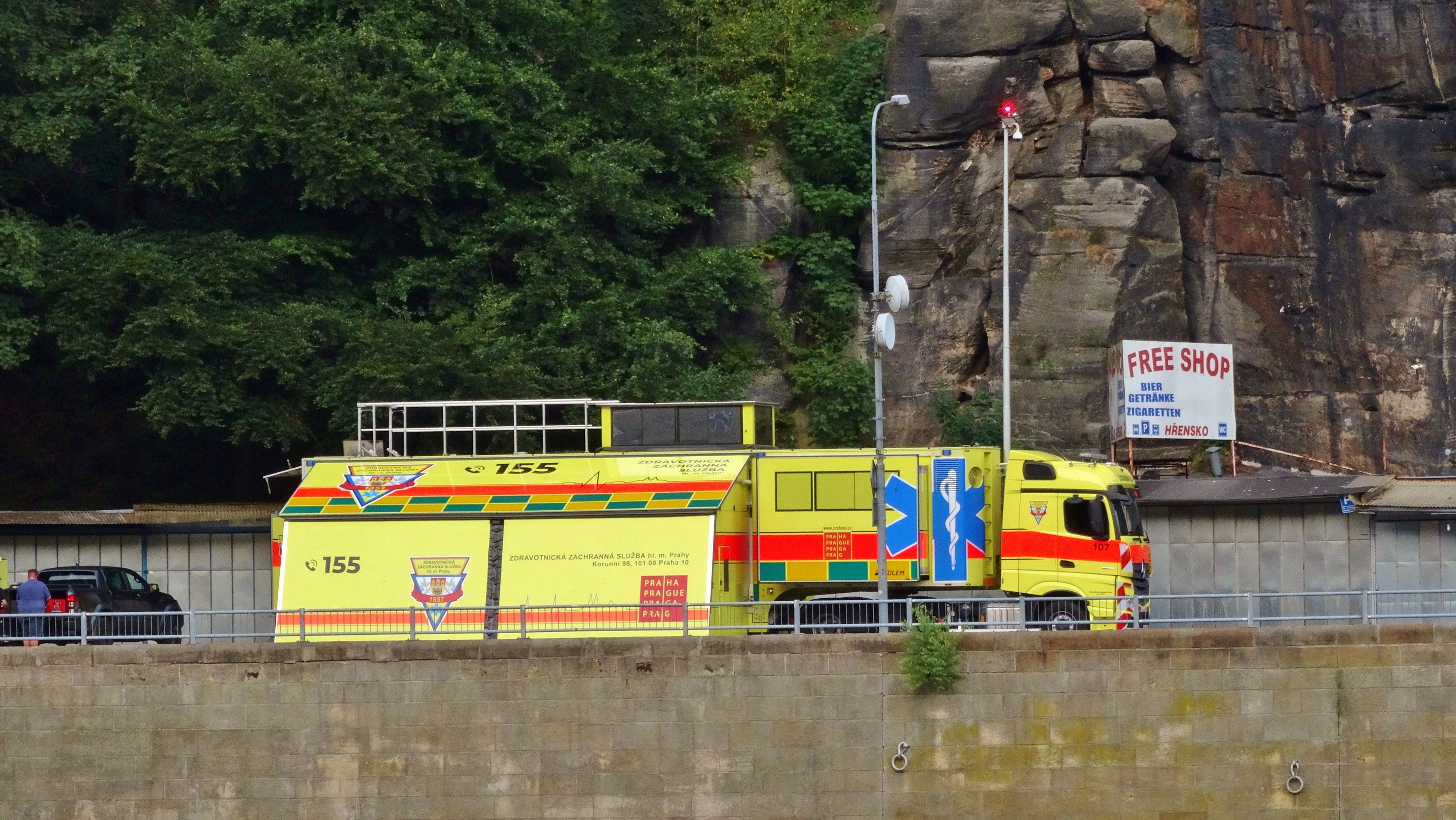 Rettungswagen am Straßenrand neben einer Klippe geparkt, mit verschiedenen Gegenständen und Bäumen im Hintergrund.