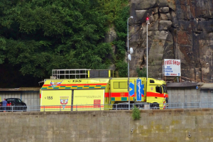 Rettungswagen am Straßenrand neben einer Klippe geparkt, mit verschiedenen Gegenständen und Bäumen im Hintergrund.