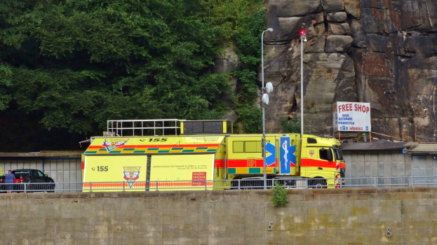 Rettungswagen am Straßenrand neben einer Klippe geparkt, mit verschiedenen Gegenständen und Bäumen im Hintergrund.