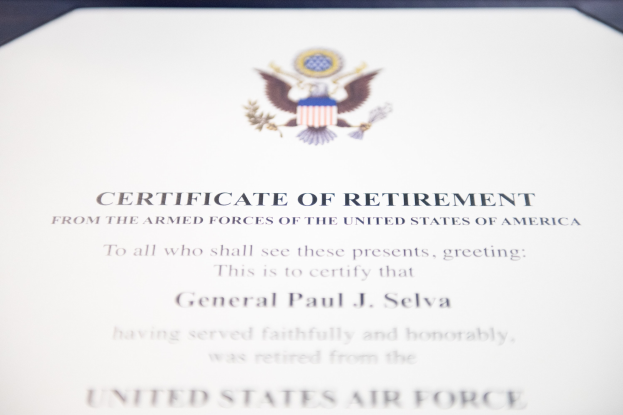 Rahmenurkunde zur Ruhestandsversetzung von der United States Air Force mit blauem Rand, schwarzer Schrift und einem zentralen Schildlogo mit einem Stern, einem Lorbeerkranz und einer "Retirement"-Banner.
