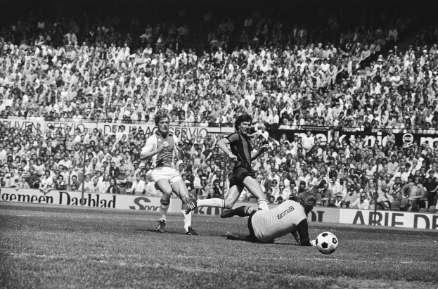 Schwarzes Foto von Männern, die auf einem Feld Fussball spielen, mit Zuschauern im Hintergrund und einer "Bundesliga 1978-79 Ajax 1-1 Hannover 96"-Aufschrift.