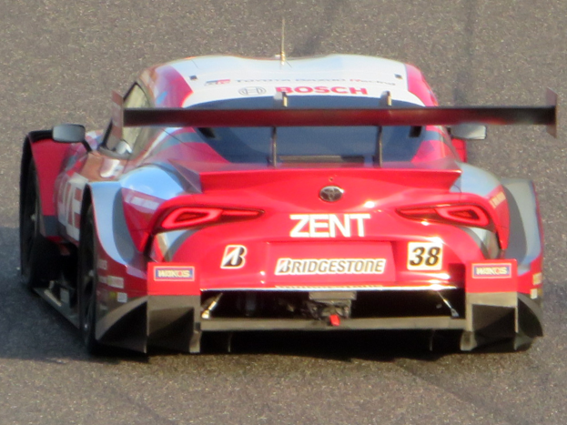 Roter und wei├čer Sportwagen mit Text und Zahlen auf einer Rennstrecke.