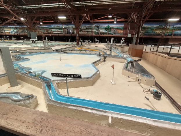 Großer Hallen-Wasserpark mit mehreren Wasserrutschen, Deckenleuchten, Wandgemälden und einem Minigolfplatz.