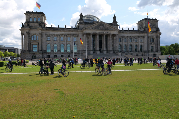Gruppe von Menschen, die vor dem Reichstaggebäude in Berlin, Deutschland, Fahrräder fahren.