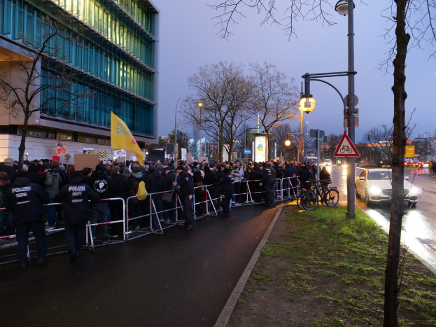 Große Gruppe von Menschen protestiert vor einem Gebäude in Berlin, hält Schilder mit Barrikaden und Fahrrädern in der Nähe.