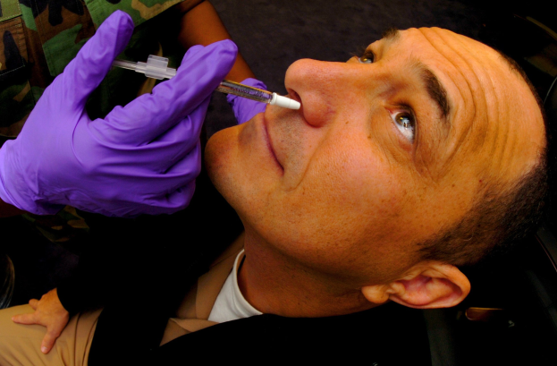 Ein Arzt in lila Handschuhen verabreicht einem Mann ein Vakzin mit einer Spritze.