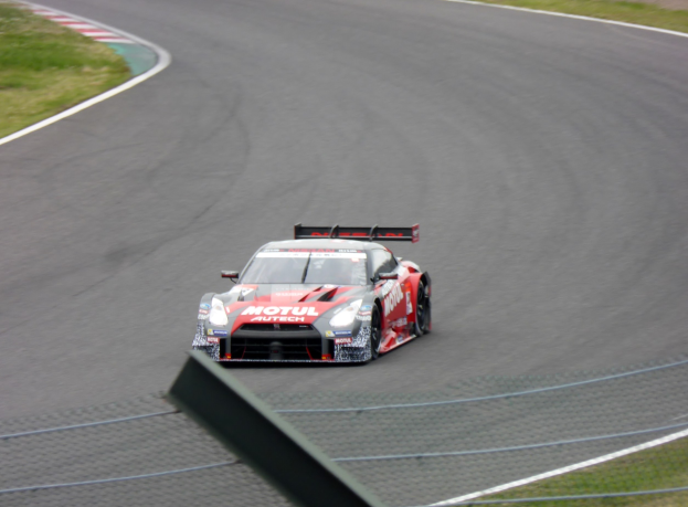 Nissan GT-R Nismo GT3 Rennwagen auf der Nürburgring 24 Stunden Rennstrecke, umgeben von grünem Gras.
