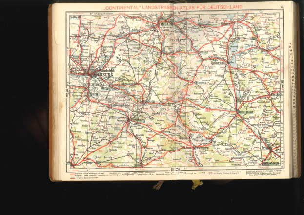 Ein aufgeschlagenes Buch, das eine detaillierte Karte von Deutschland mit Straßen und Autobahnen zeigt, vor einem dunklen Hintergrund.