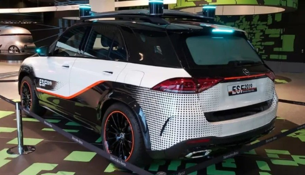 Mercedes-Benz E-Klasse Electric SUV auf der IAA in Frankfurt zu sehen, umgeben von Absperrpollern mit Seilen und Lichtern, mit einem weiteren Fahrzeug und einer textbedruckten Wand im Hintergrund.