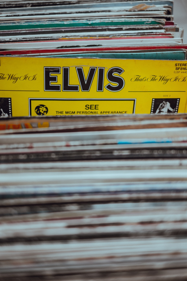 Ein ordentlicher Stapel Elvis-Presley-Platten mit sichtbaren Titeln auf einem leicht unscharfen Hintergrund.
