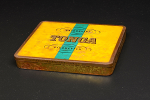 Ein gelb-blauer Tonga-Zigaretten-Tin auf einem schwarzen Tisch, mit Text, der die Marke und Art des Tabaks angibt.
