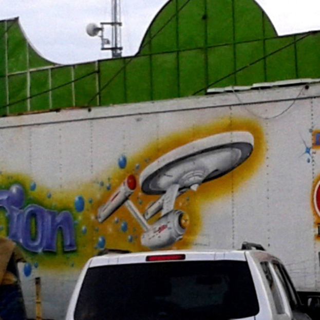 Ein Auto vor einer Wand mit einem Gemälde darauf geparkt.