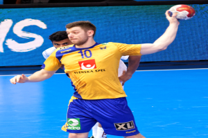 Ein Mann in einem gelben T-Shirt und blauen Shorts hält einen Handball auf einem Court, mit einem Bildschirm im Hintergrund, der "Svenský Spel Handball World Cup 2019" anzeigt.