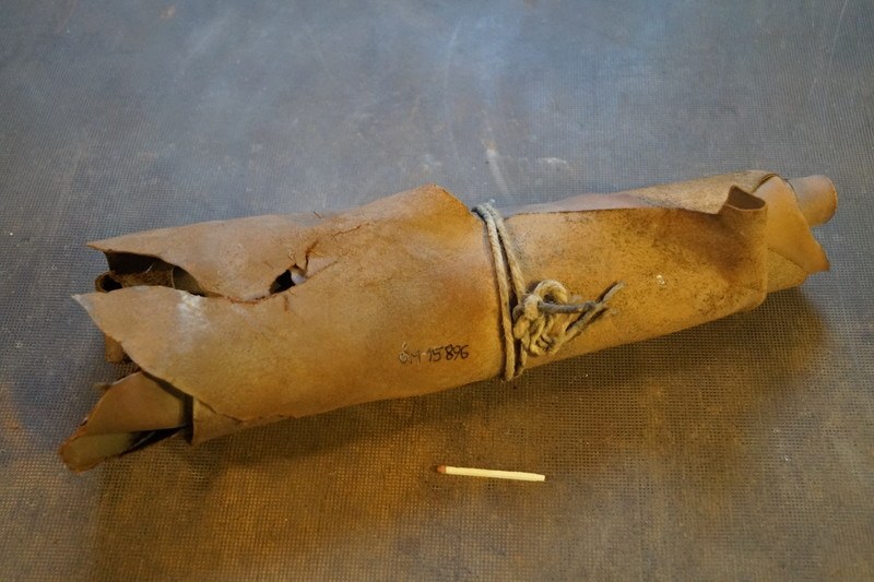 Ein brauner Papiertüte in Form einer Granate, mit einem Seil gebunden, liegt auf einem Tisch neben einer Zigarette.