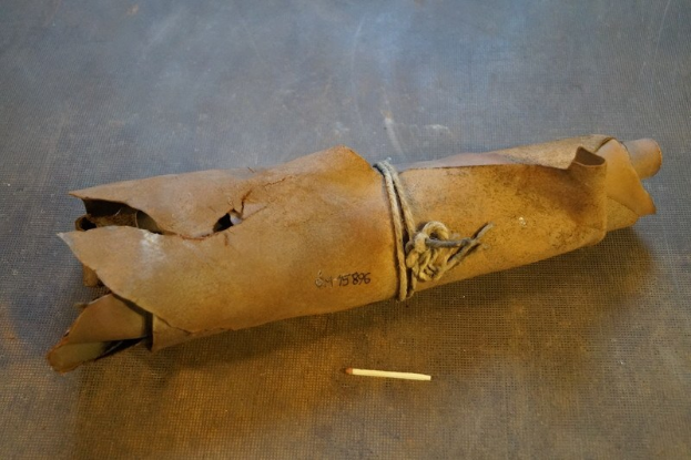 Ein brauner Papiertüte in Form einer Granate, mit einem Seil gebunden, liegt auf einem Tisch neben einer Zigarette.