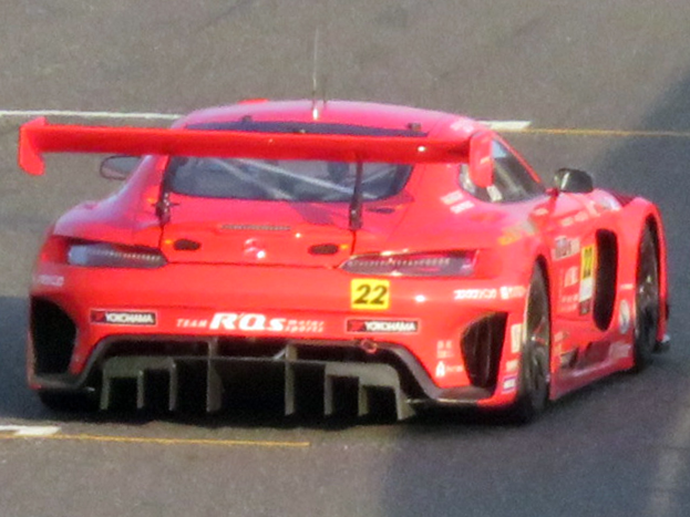Roter Porsche 911 GTS Rennwagen auf einer Rennstrecke mit aerodynamischem Design, großem Heckspoiler und Flügel, schwarzen Rädern und leistungsstarkem Motor.